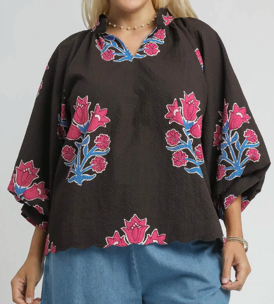 Brown blouse with floral embroidery worn by a person on a plain background