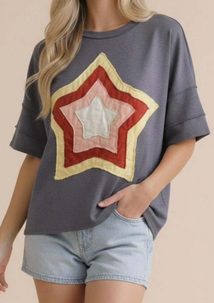 Person wearing a gray t-shirt with a star design and denim shorts on a beige background