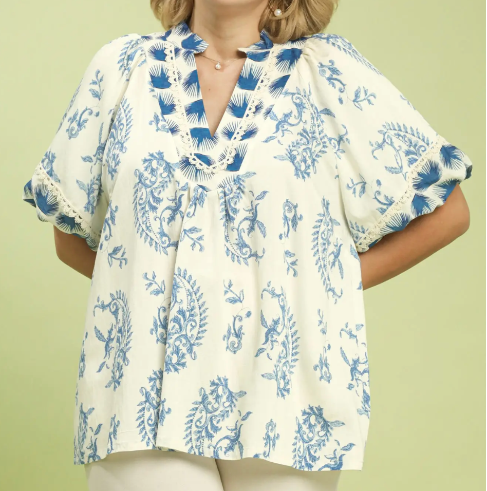 Woman wearing a white blouse with blue floral pattern on a light green background