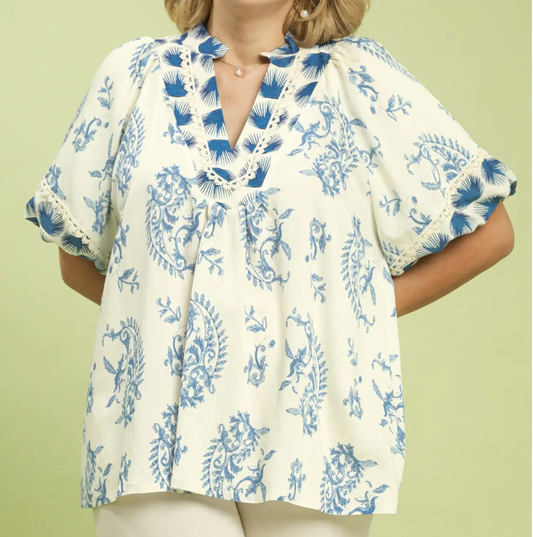 Woman wearing a white blouse with blue floral pattern on a light green background